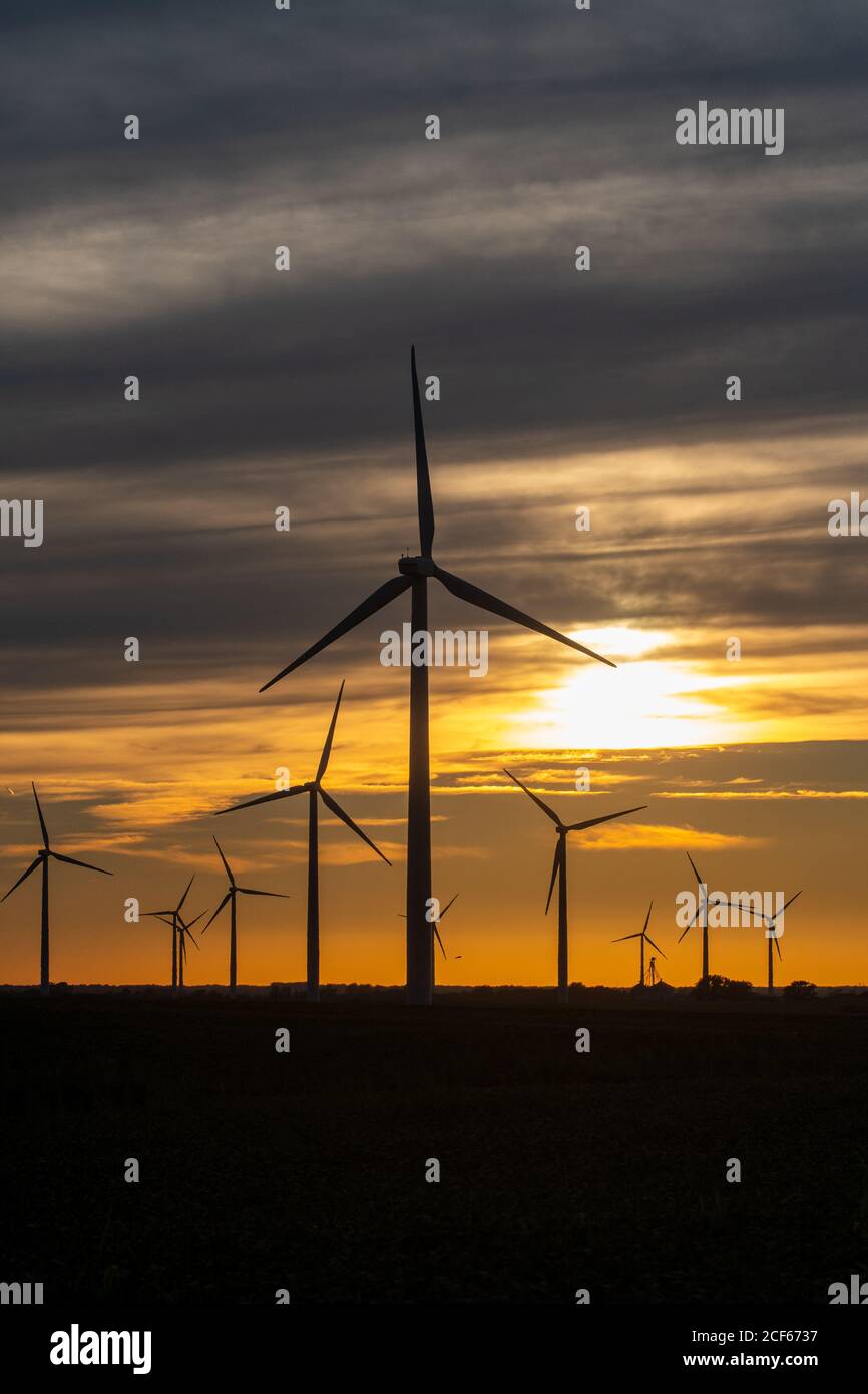 The sun sets on a field of wind turbines at a wind farm in Indiana, United States Stock Photo