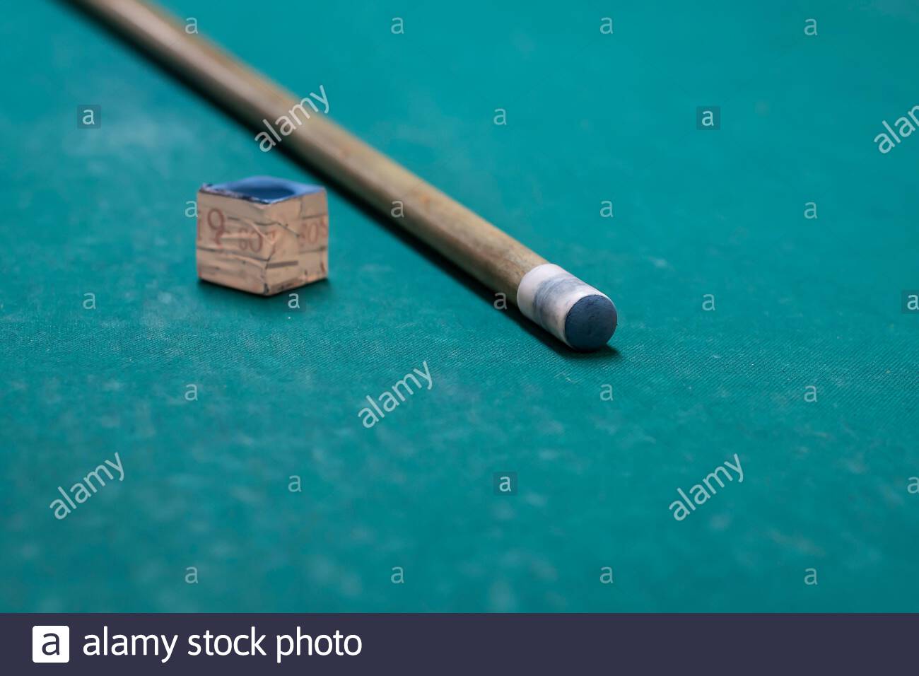 A cue stick and chalk on a pool table Stock Photo