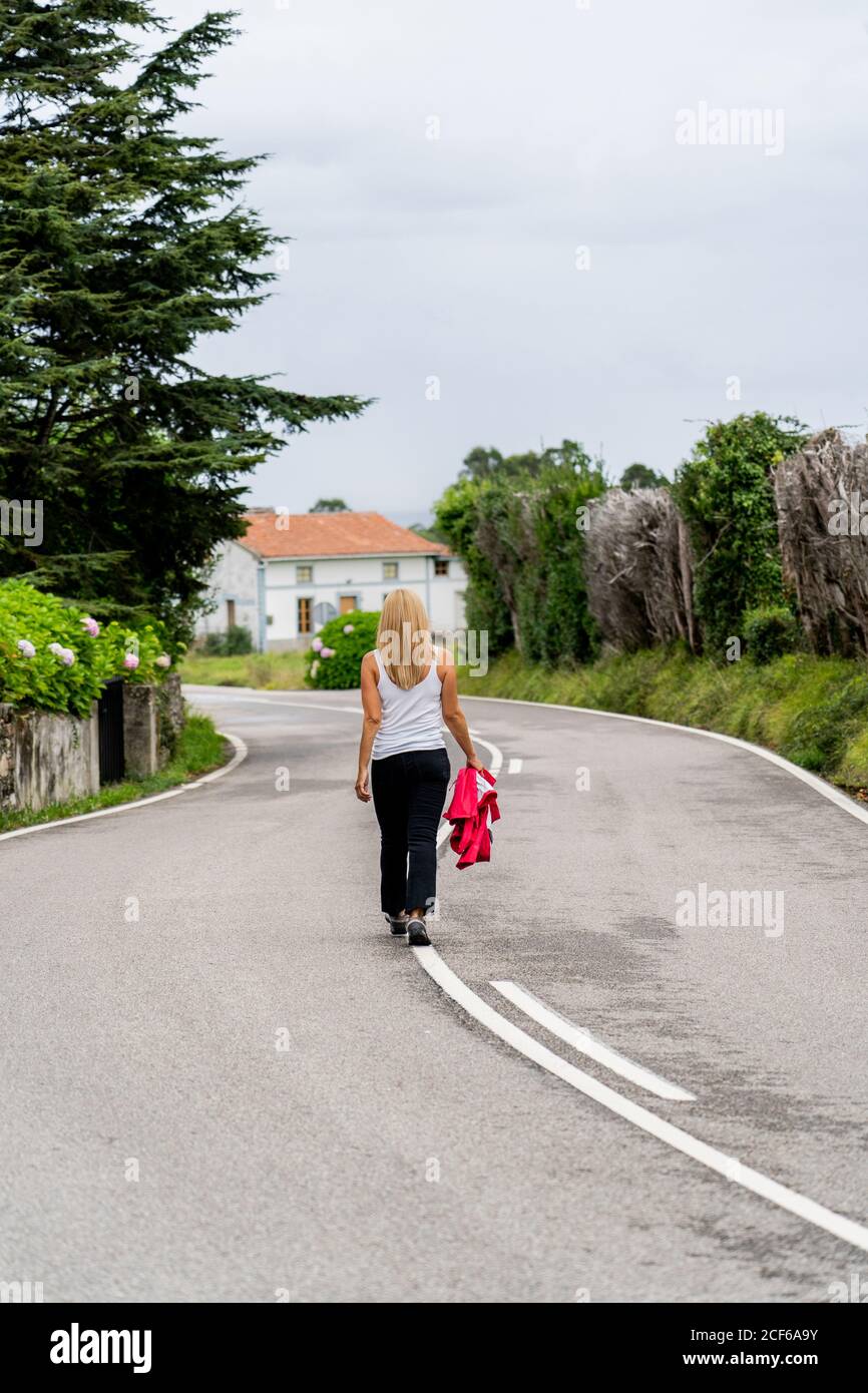 Joyful Woman walking on marked road looking away Stock Photo