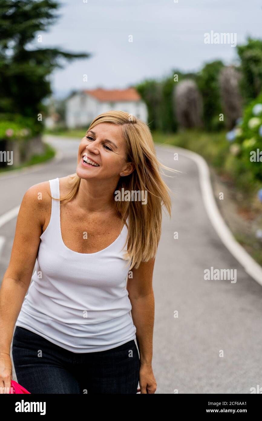 Joyful Woman walking on marked road looking away Stock Photo
