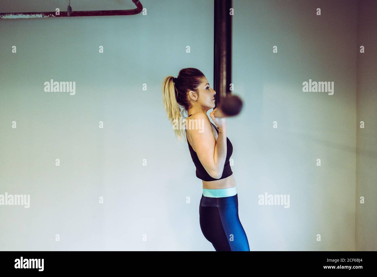 Young Woman doing pull ups in gym Stock Photo