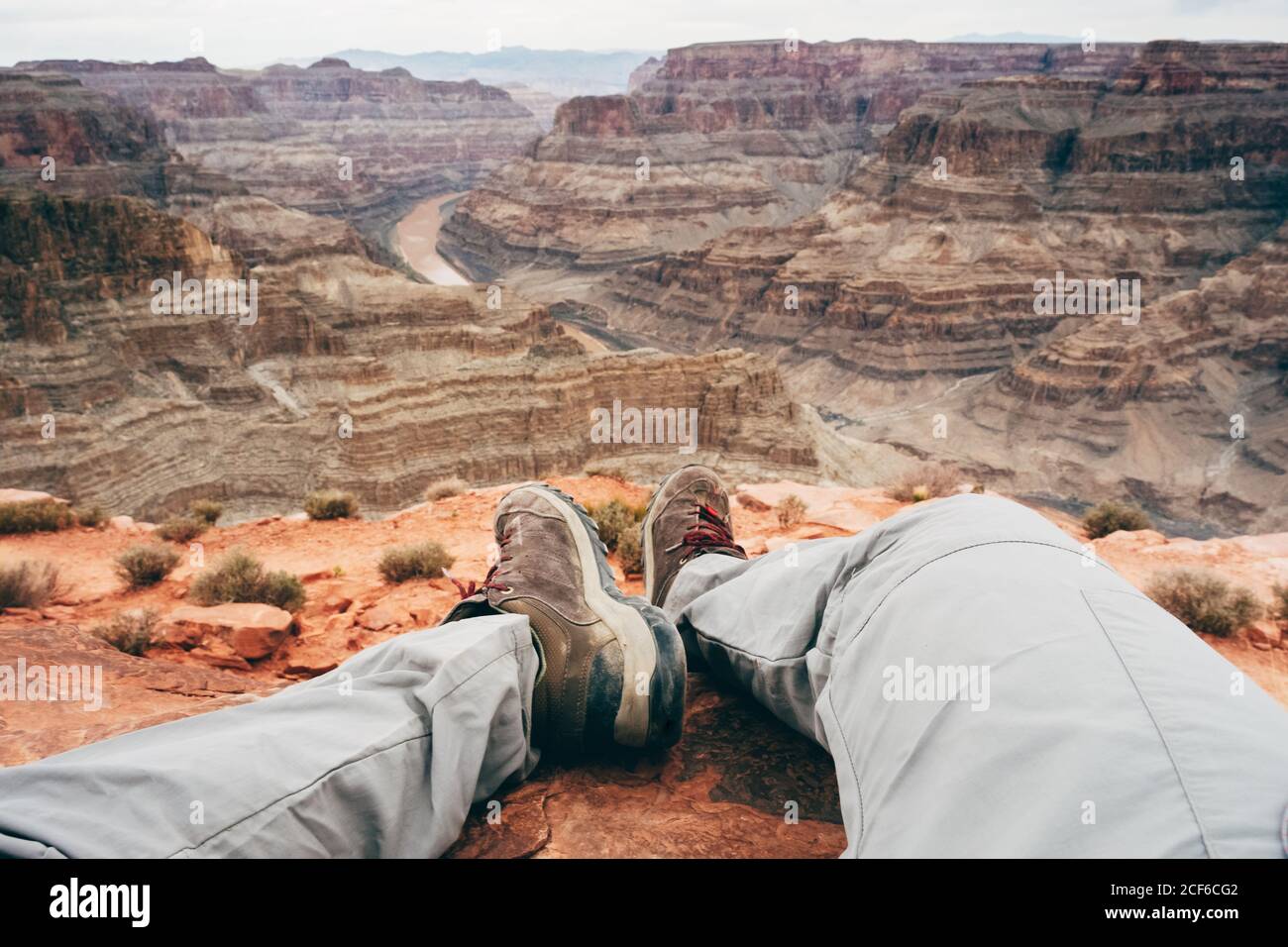 Crop tired Man recreating on edge of cliff at scenic canyon in USA Stock Photo