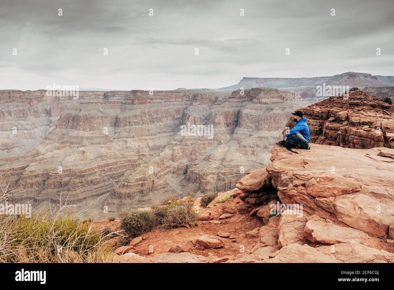 Side view of weary male relaxing on edge of cliff at canyon in USA and admiring landscape Stock Photo