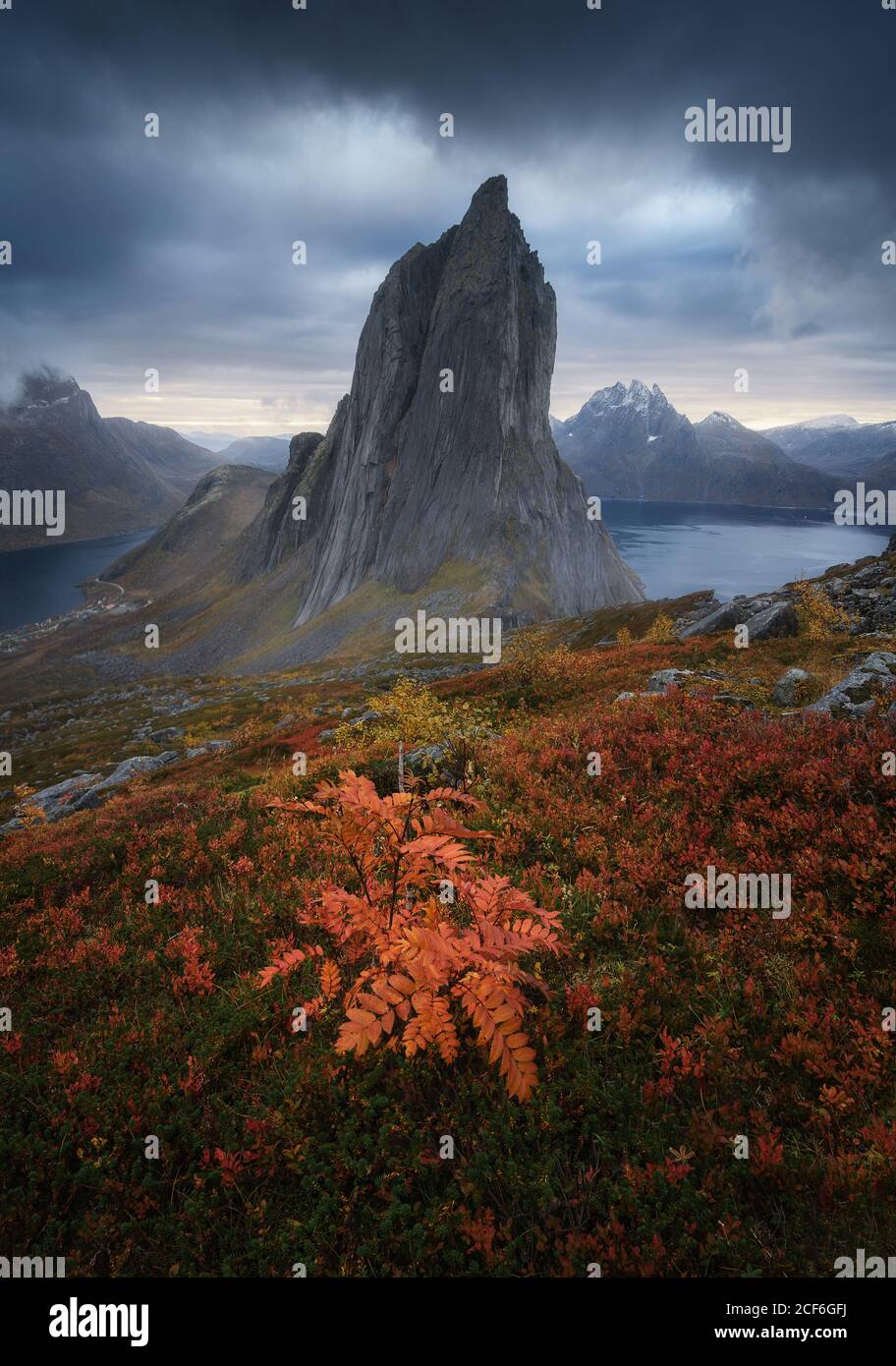 Segla mountain located in grassy valley near calm basin against dark overcast sky on island of Senja, Norway Stock Photo