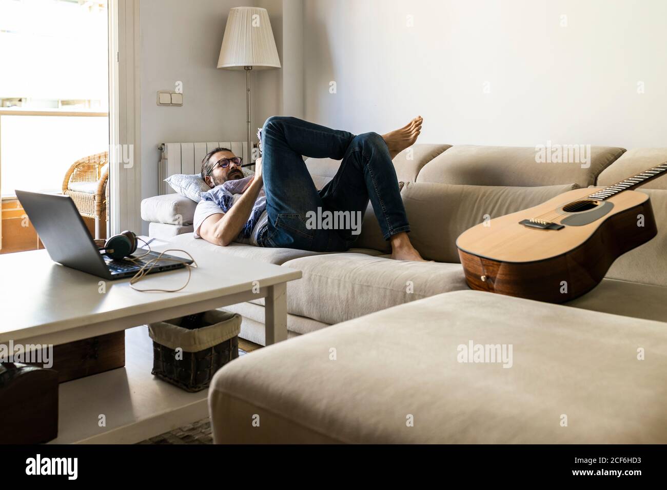 Man writing notes on couch in cozy living room Stock Photo