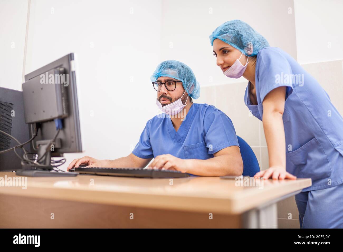 Team of surgeons, man and Woman using the computer before the surgery and committing the details Stock Photo