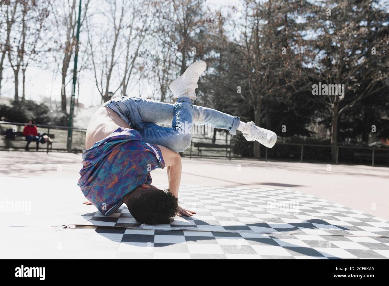 Young athletic guy practicing break dance in park in sunny weather Stock Photo