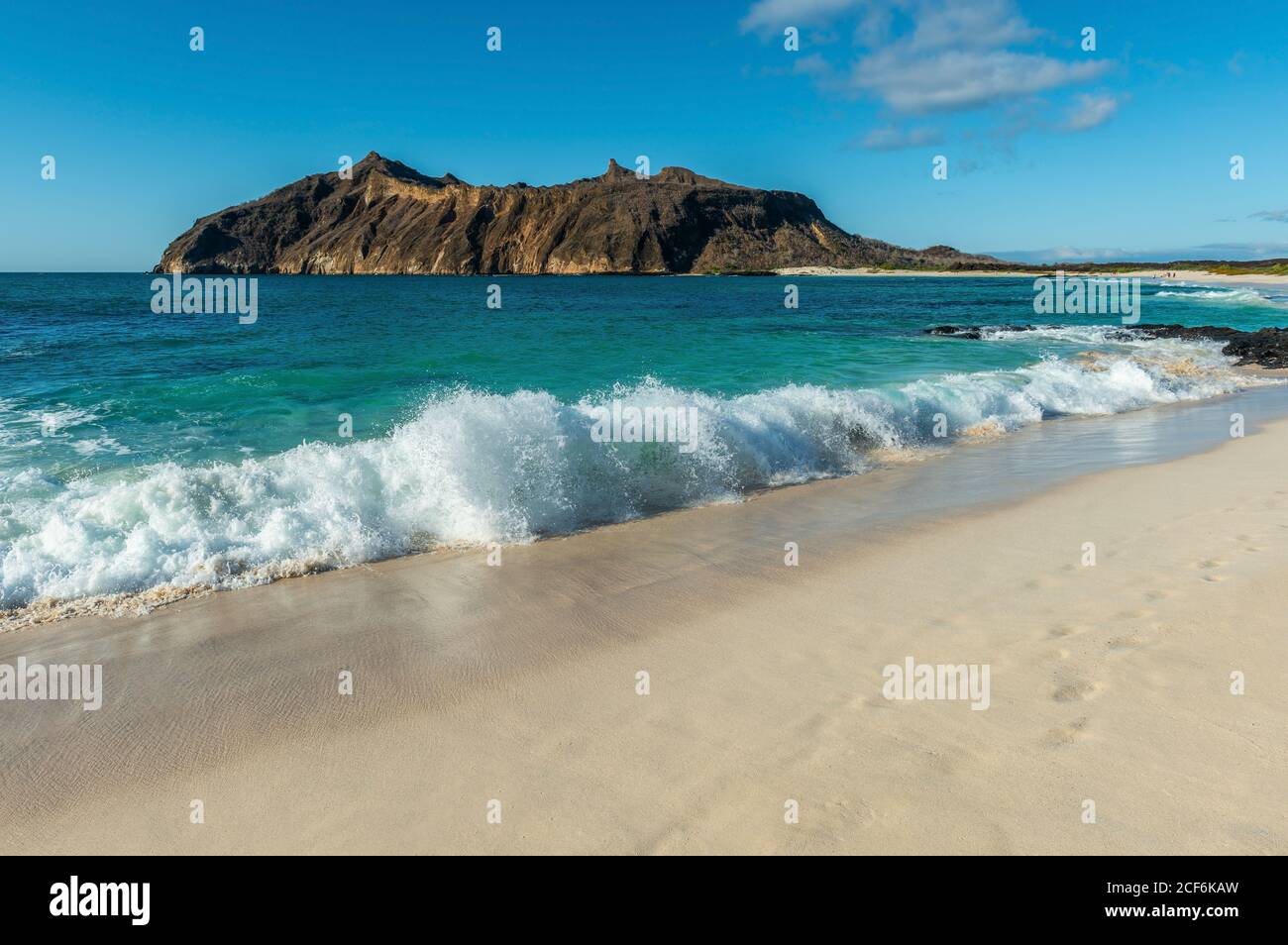 Landscape of strong waves by the beach in Stephens Bay with Witch Hill in the background, San Cristobal island, Galapagos, Ecuador. Stock Photo