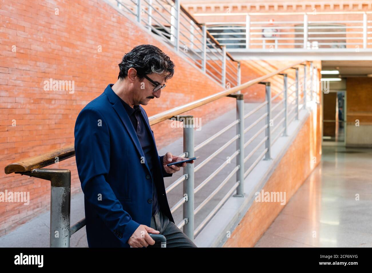 Aged man standing with baggage and talking on smartphone Stock Photo