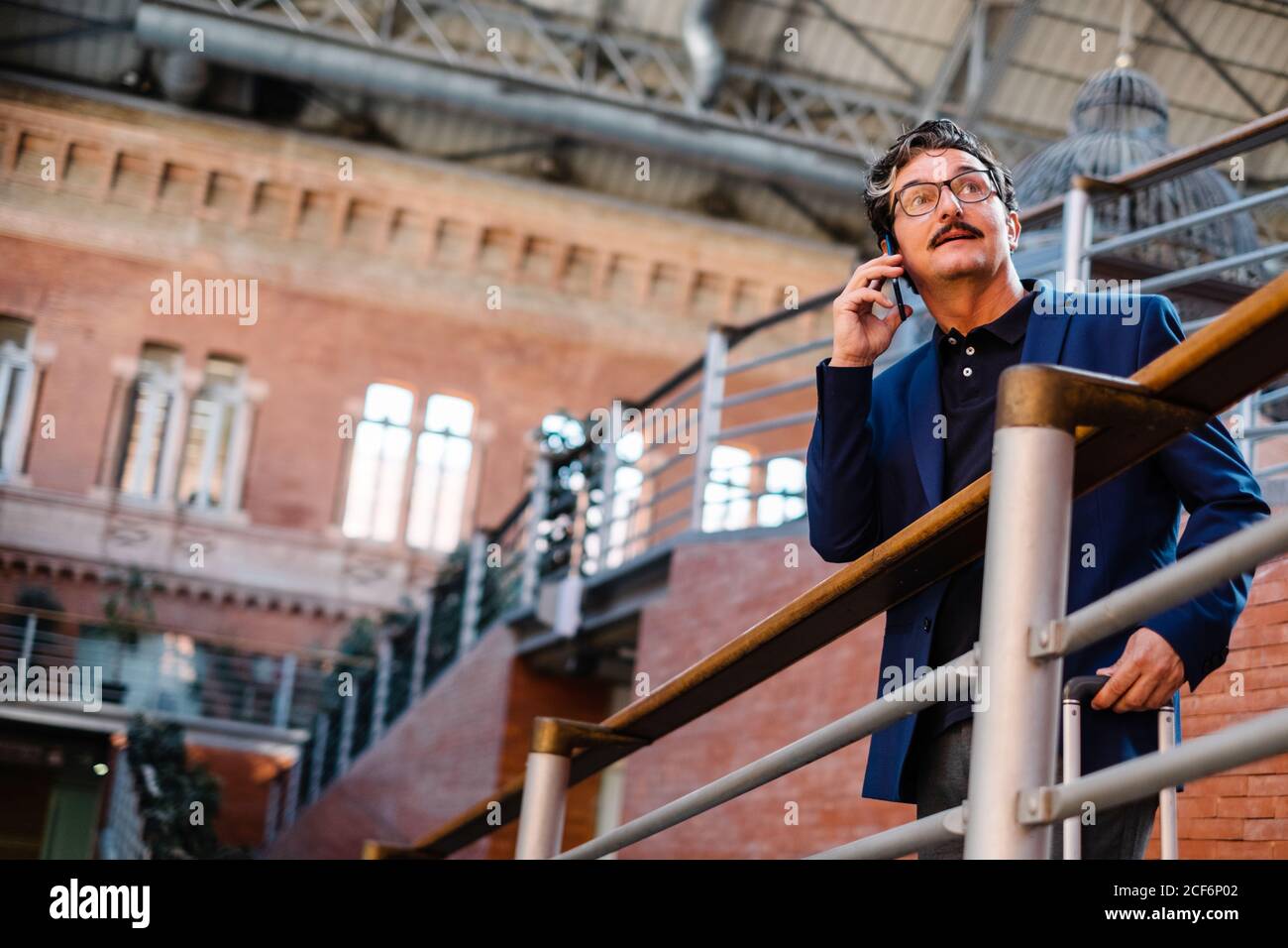 Aged man standing with baggage and talking on smartphone Stock Photo