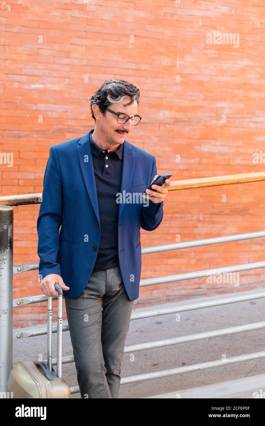 Aged man standing with baggage and talking on smartphone Stock Photo