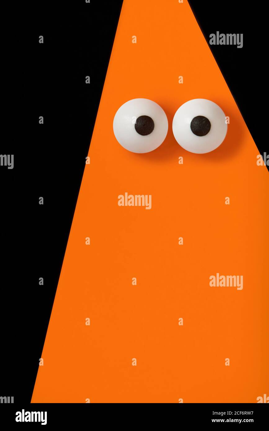 Halloween background, Orange ghost with bulging eyes on black, copy space. Stock Photo