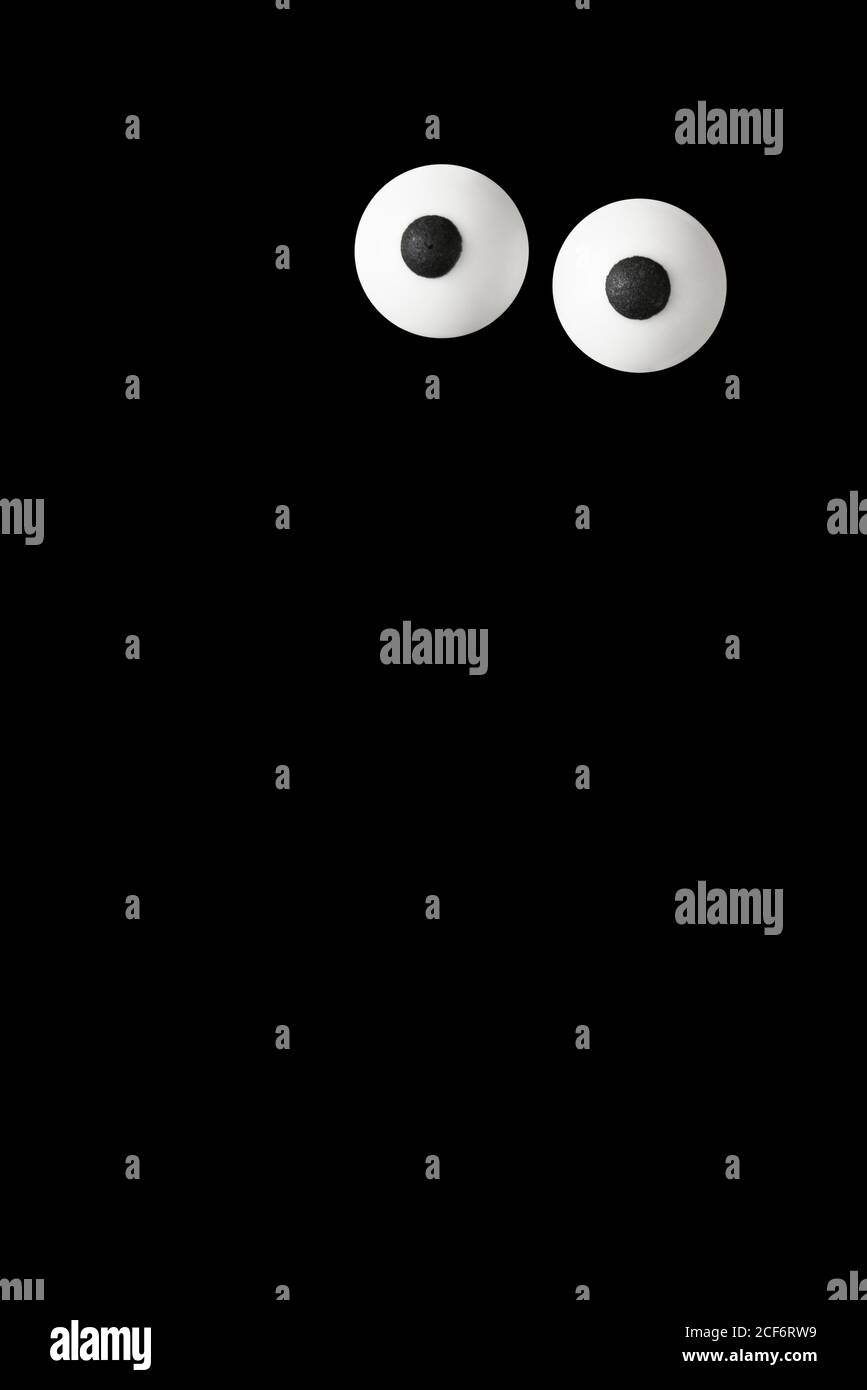 Halloween background, pair of white bulged eyes in the dark, black