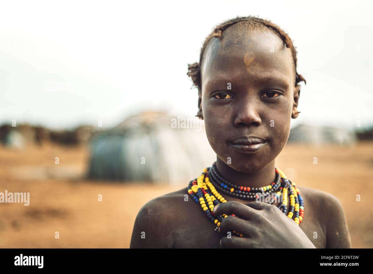 Omo Valley, Ethiopia - November 09, 2018: Cute girl looking at camera while standing on Dassanech tribe village in Omo Valley, Ethiopia Stock Photo