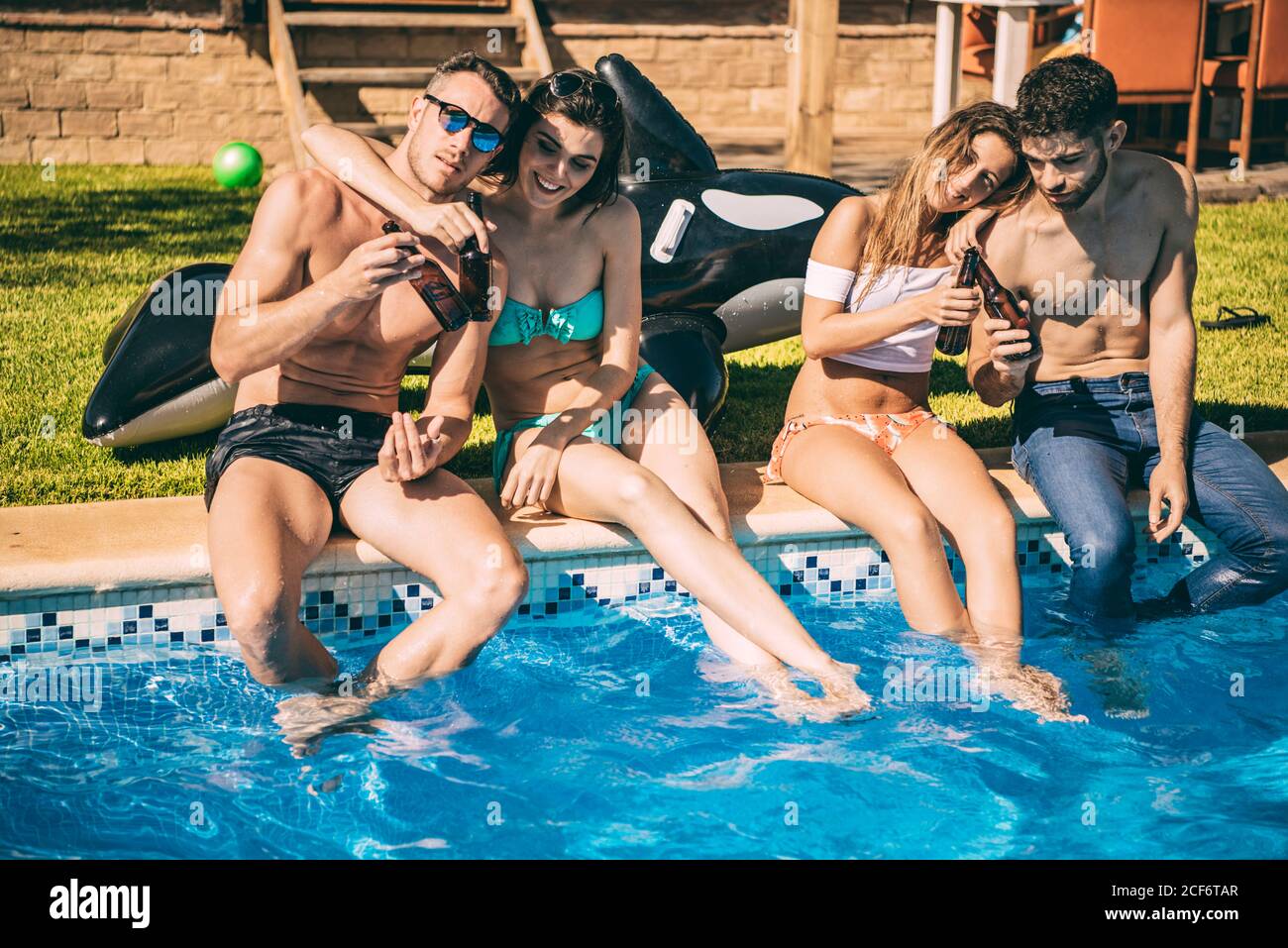 Young friends having drinks in pool Stock Photo