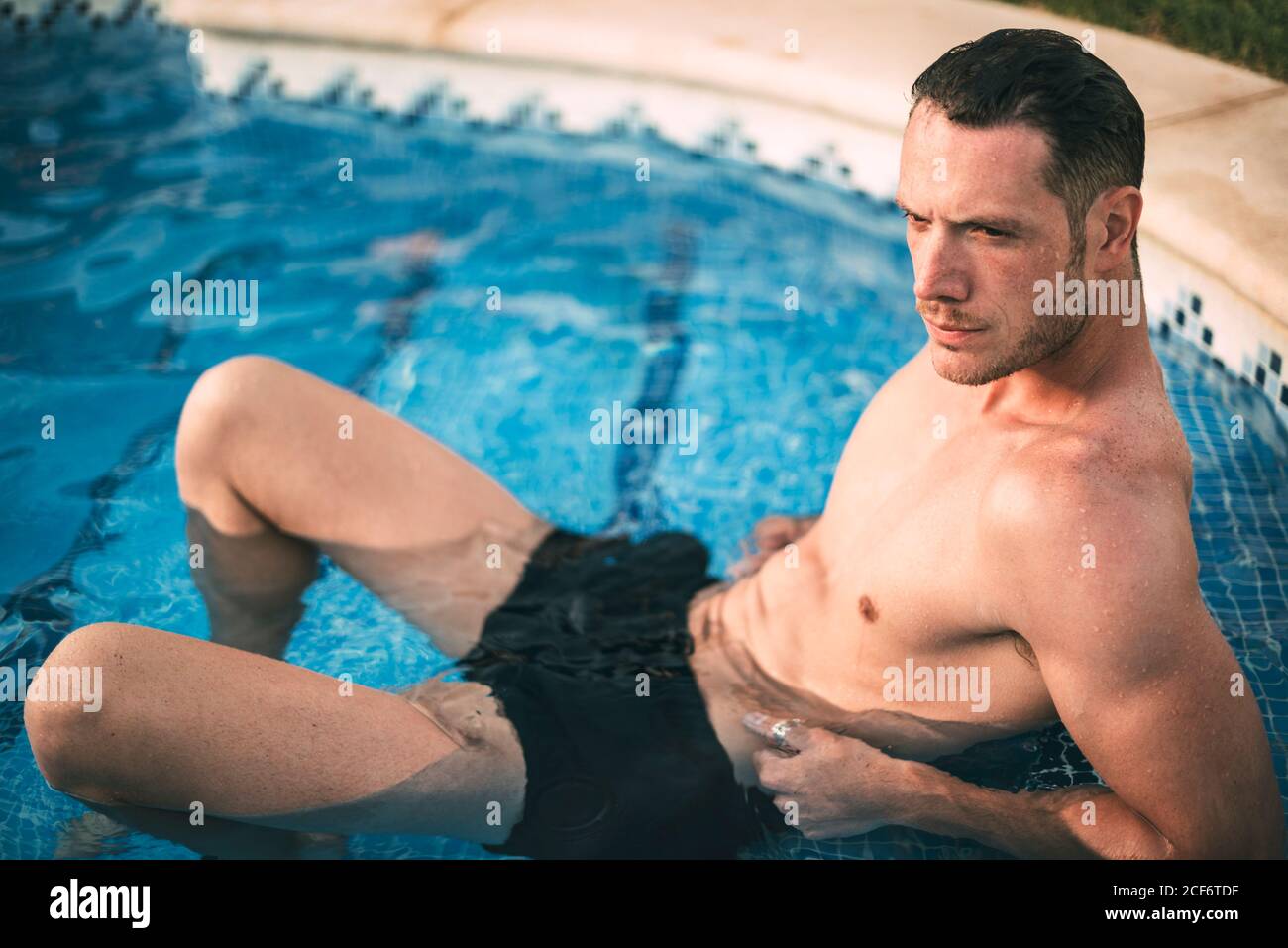 man lying on steps in pool Stock Photo