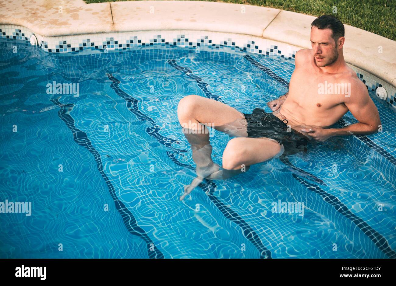 man lying on steps in pool Stock Photo