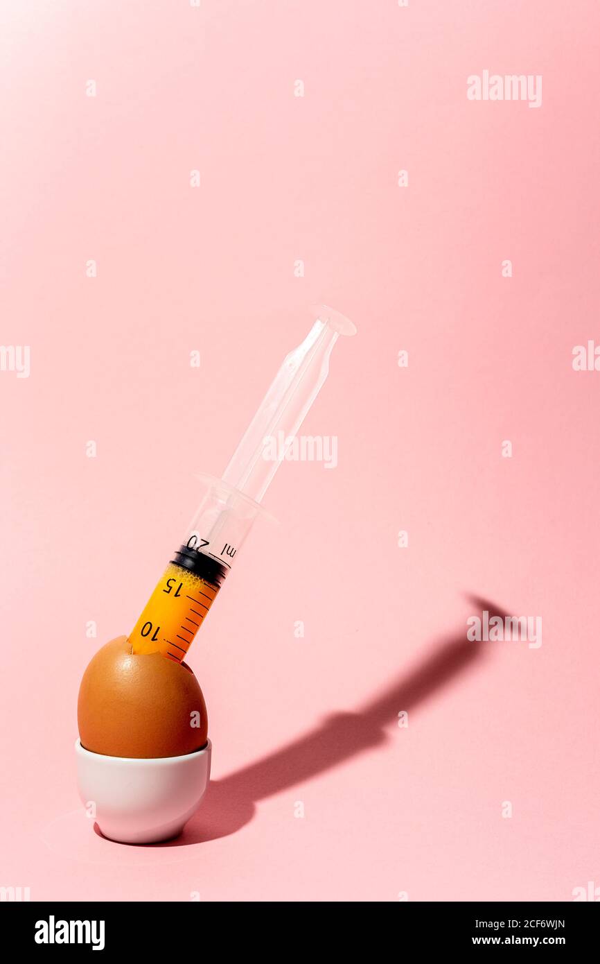 Egg with syringe in eggcup Stock Photo
