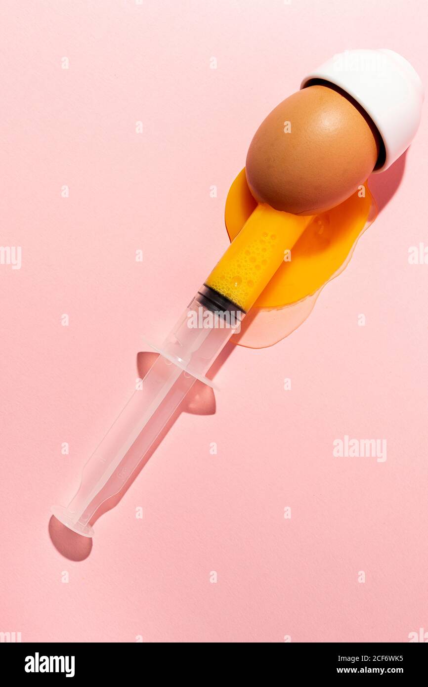 Syringe sucking yolk out of raw egg Stock Photo