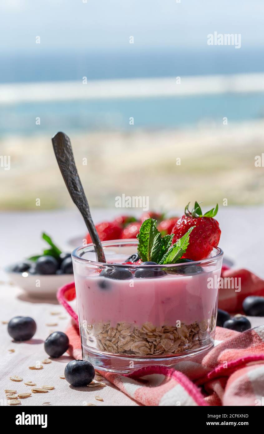 Homemade yogurt with strawberries, blueberries and cereals with pink tablecloth and sunlight.Healthy food concept.Vegan food Stock Photo