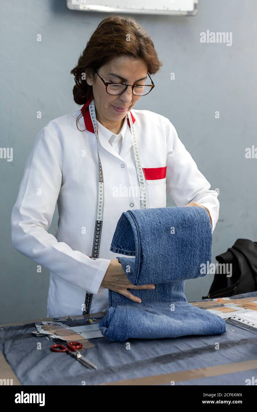 Woman worker in textile factory checking the quality of the garments. Industrial production Stock Photo