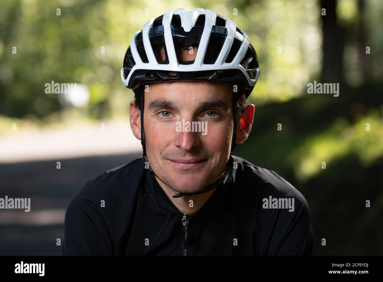 Confident adult man in bike helmet smiling and looking at camera on blurred background of park during training Stock Photo - Alamy Confident adult man in bike helmet smiling and looking at camera on blurred background of park during training Stock Photo - Alamy