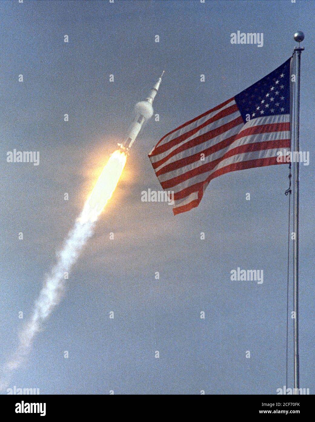 The American flag heralds the flight of Apollo 11, the first Lunar landing mission. The Apollo 11 Saturn V space vehicle lifted off with astronauts Neil A. Armstrong, Michael Collins and Edwin E. Aldrin, Jr., at 9:32 a.m. EDT July 16, 1969, from Kennedy Space Center's Launch Complex 39A. During the planned eight-day mission, Armstrong and Aldrin will descend in a lunar module to the Moon's surface while Collins orbits overhead in the Command Module. The two astronauts are to spend 22 hours on the Moon, including two and one-half hours outside the lunar module. They will gather samples of lunar Stock Photo