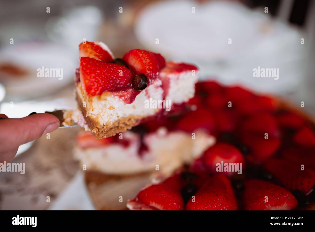 Woman hand cutting strawberry cake with knife Stock Photo