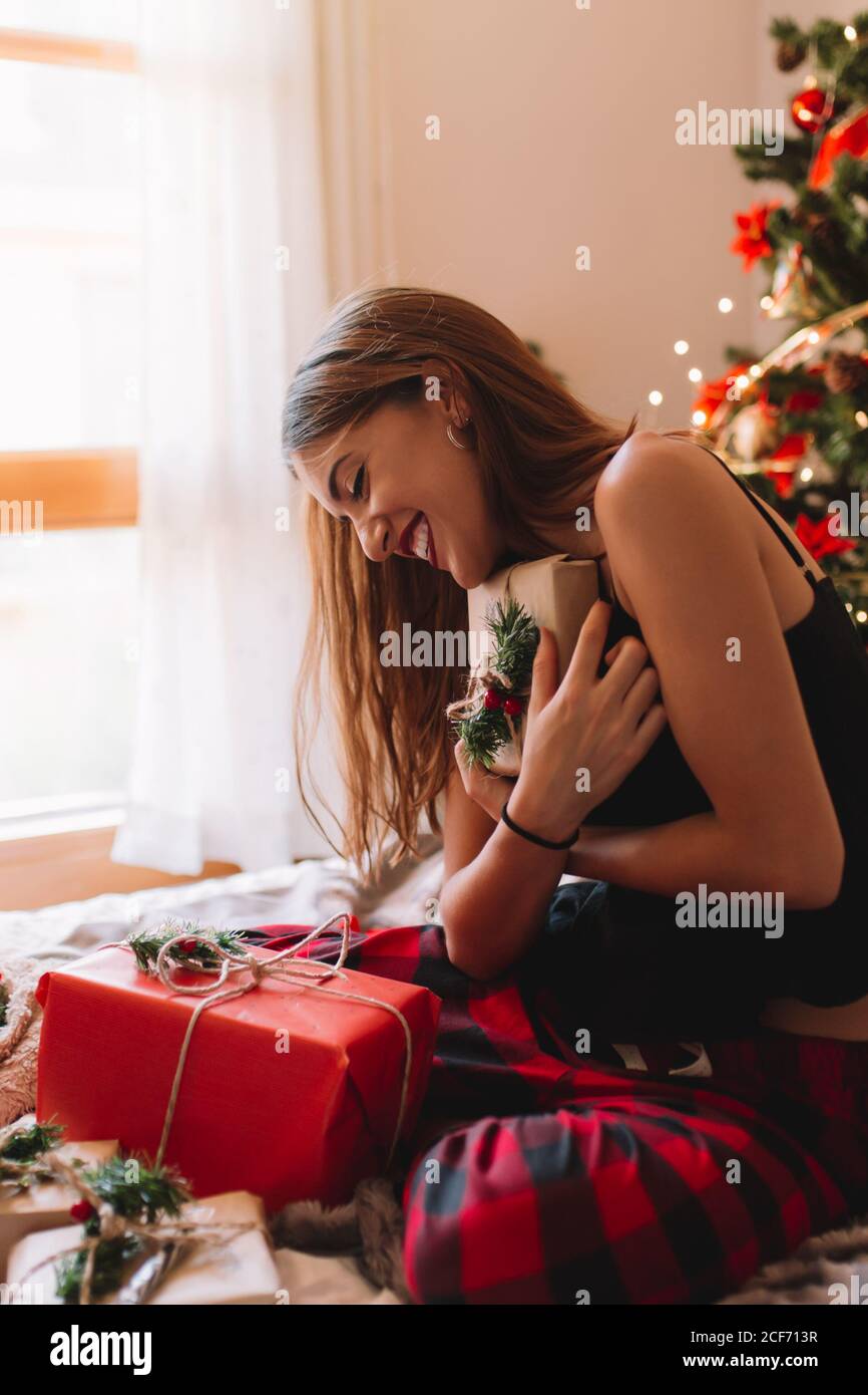 Portrait of beautiful and happy women opening gifts in cozy bed near christmas tree. Stock Photo