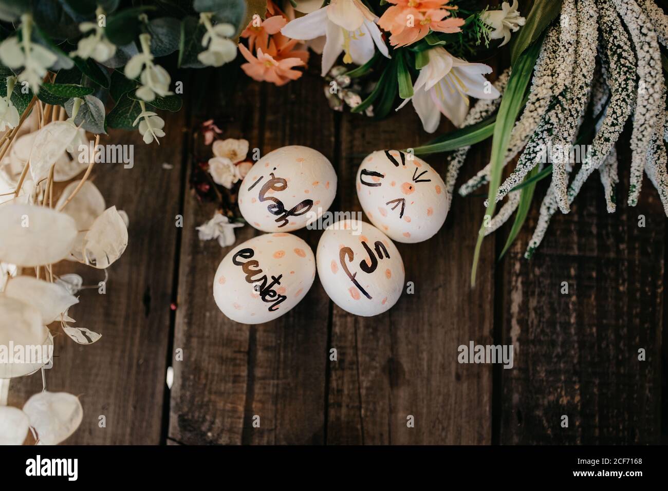 Easter eggs hand painted by children with messages in a wooden table and flowers Stock Photo