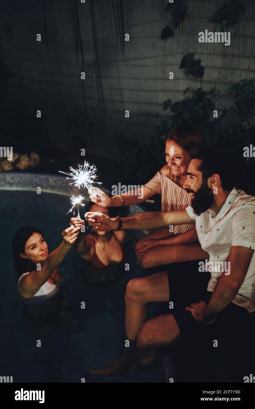 Cheerful friends burning sparkles near pool Stock Photo