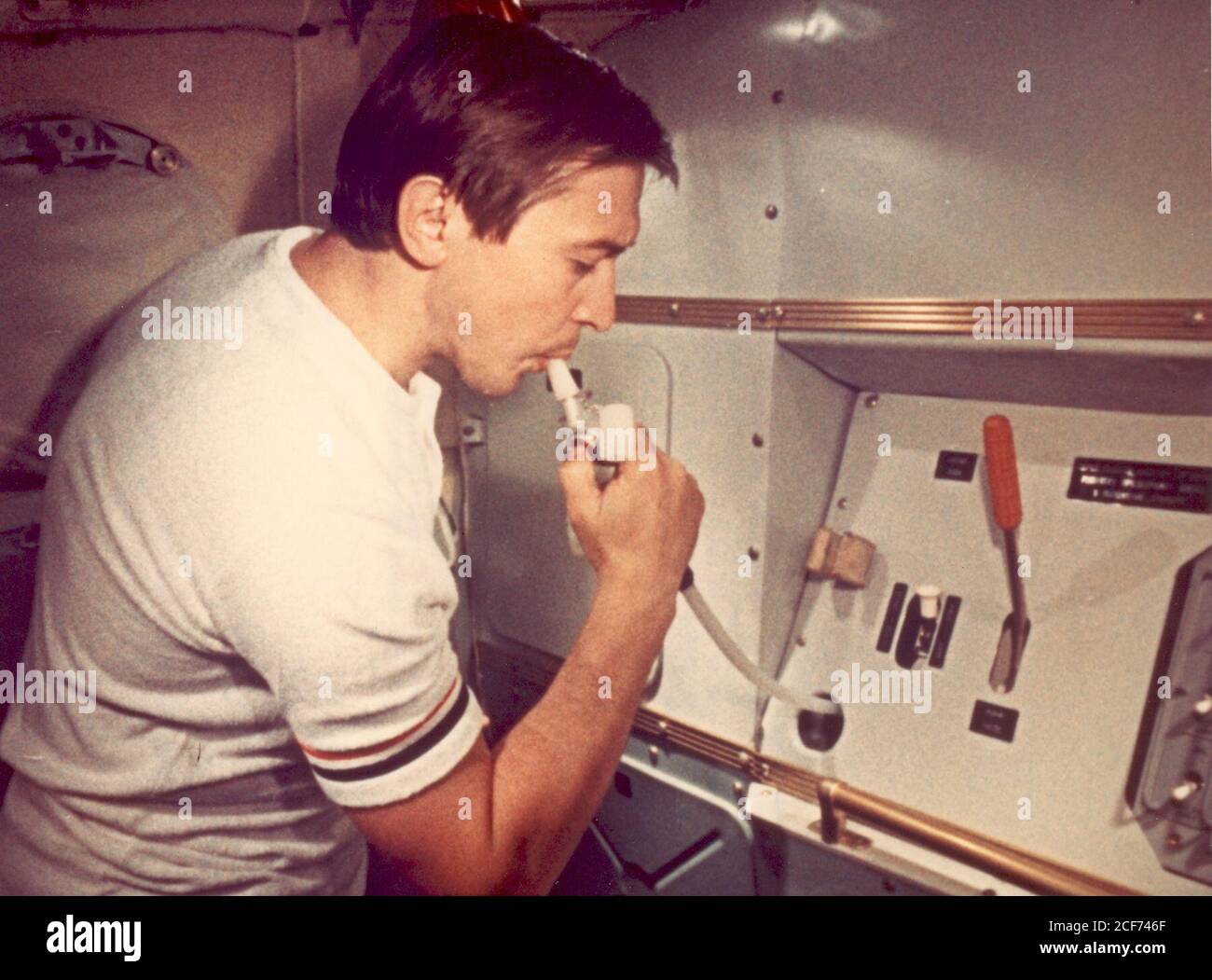 An interior view of the orbital module of a Soviet Soyuz spacecraft mock-up, located at the Cosmonaut Training Center (Star City) near Moscow. This view shows a Soviet test engineer drinking from a water dispenser. The orbital module is one of three major components of the Soyuz spacecraft. The other two components are the descent vehicle and the instrument assembly module. This photograph was made from a frame of the 35mm motion picture film entitled 'Checkout of the Compatibility of Equipment in the Soyuz Spacecraft Mock-up Stock Photo