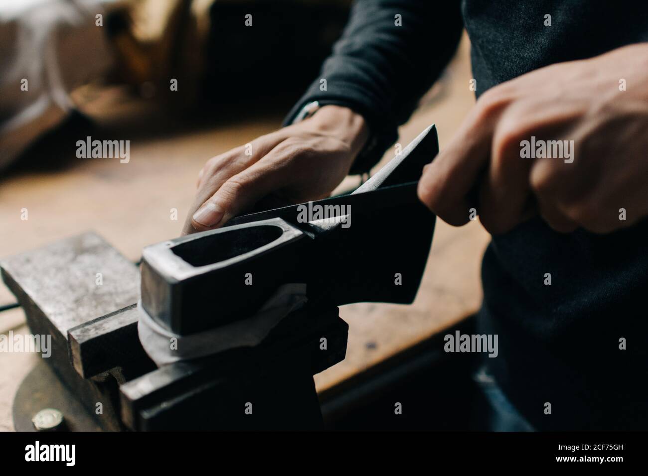 Crop craftsman checking axe in workshop Stock Photo