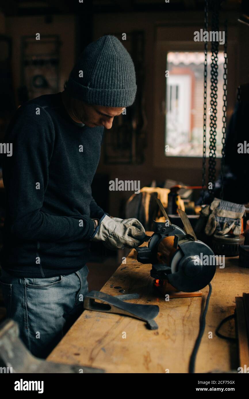 Crop craftsman checking axe in workshop Stock Photo
