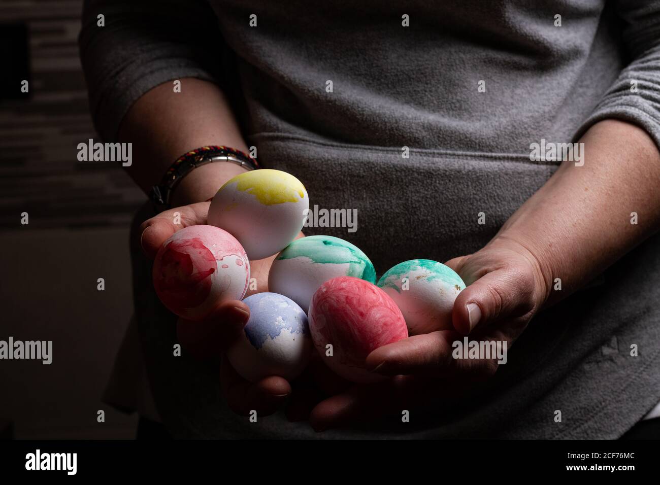 Crop lady holding heap of colored chicken eggs in obscurity Stock Photo