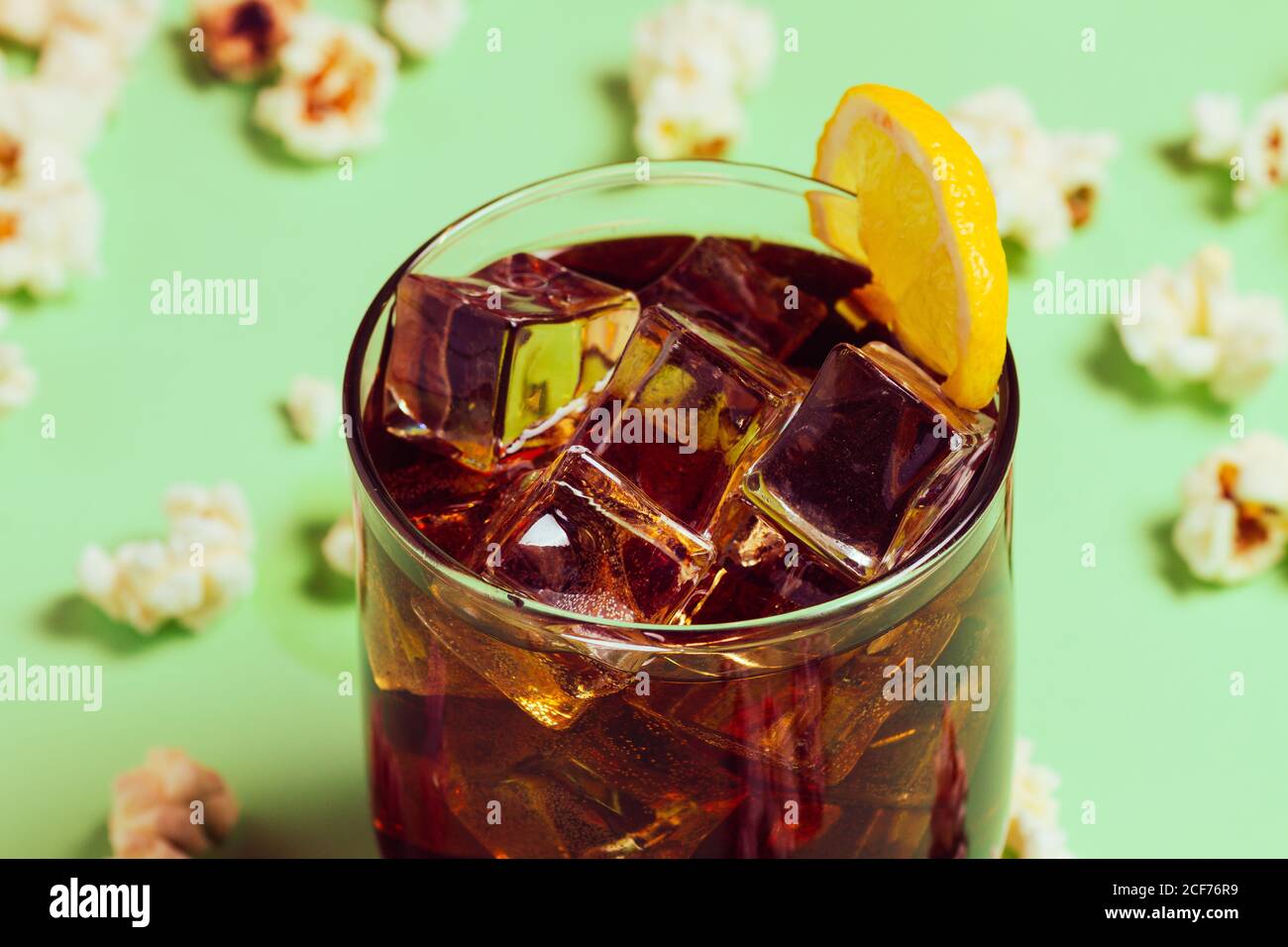 Popcorn on table near drink in glass with ice and lemon Stock Photo