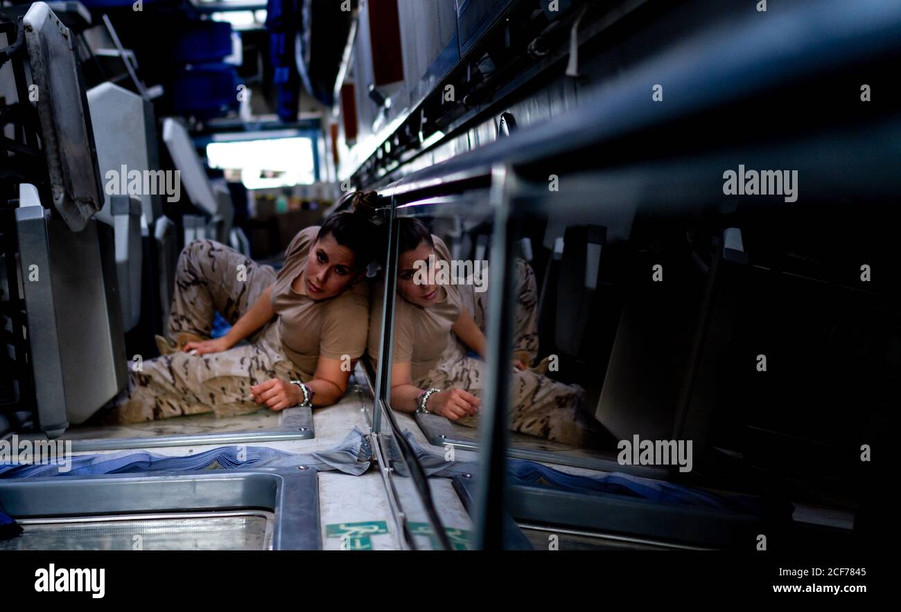 Female soldier looking at camera while lying on floor of contemporary military transport Stock Photo
