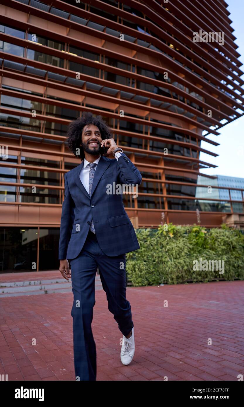 Ethnic smiling businessman talking on smartphone Stock Photo