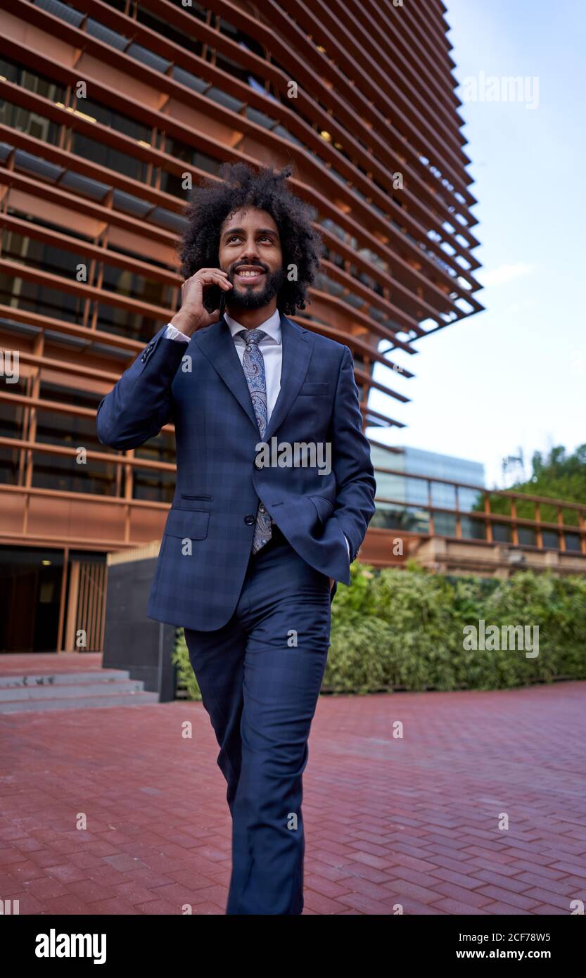 Ethnic smiling businessman talking on smartphone Stock Photo