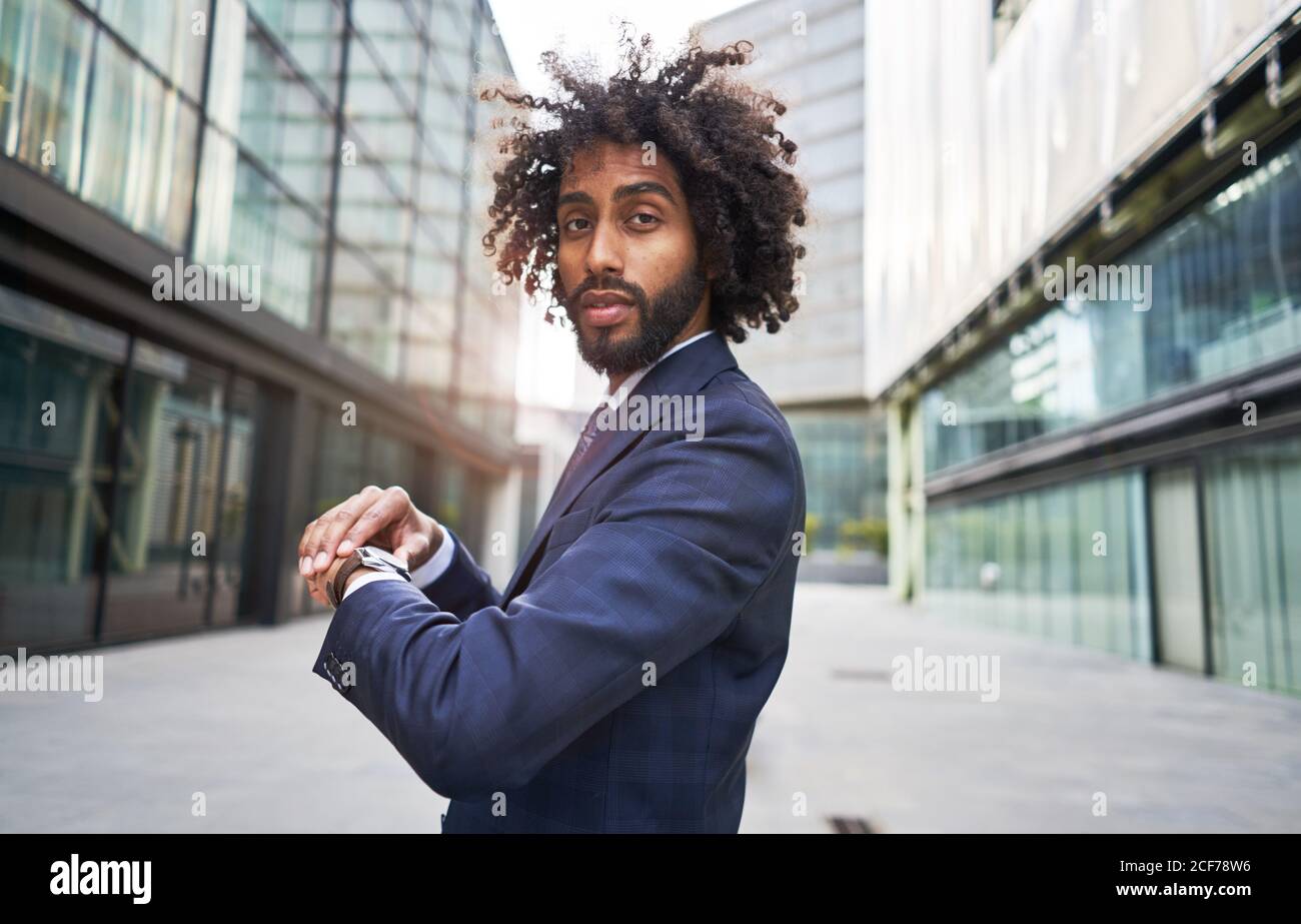 Joyful ethnic worker standing outside and checking time Stock Photo