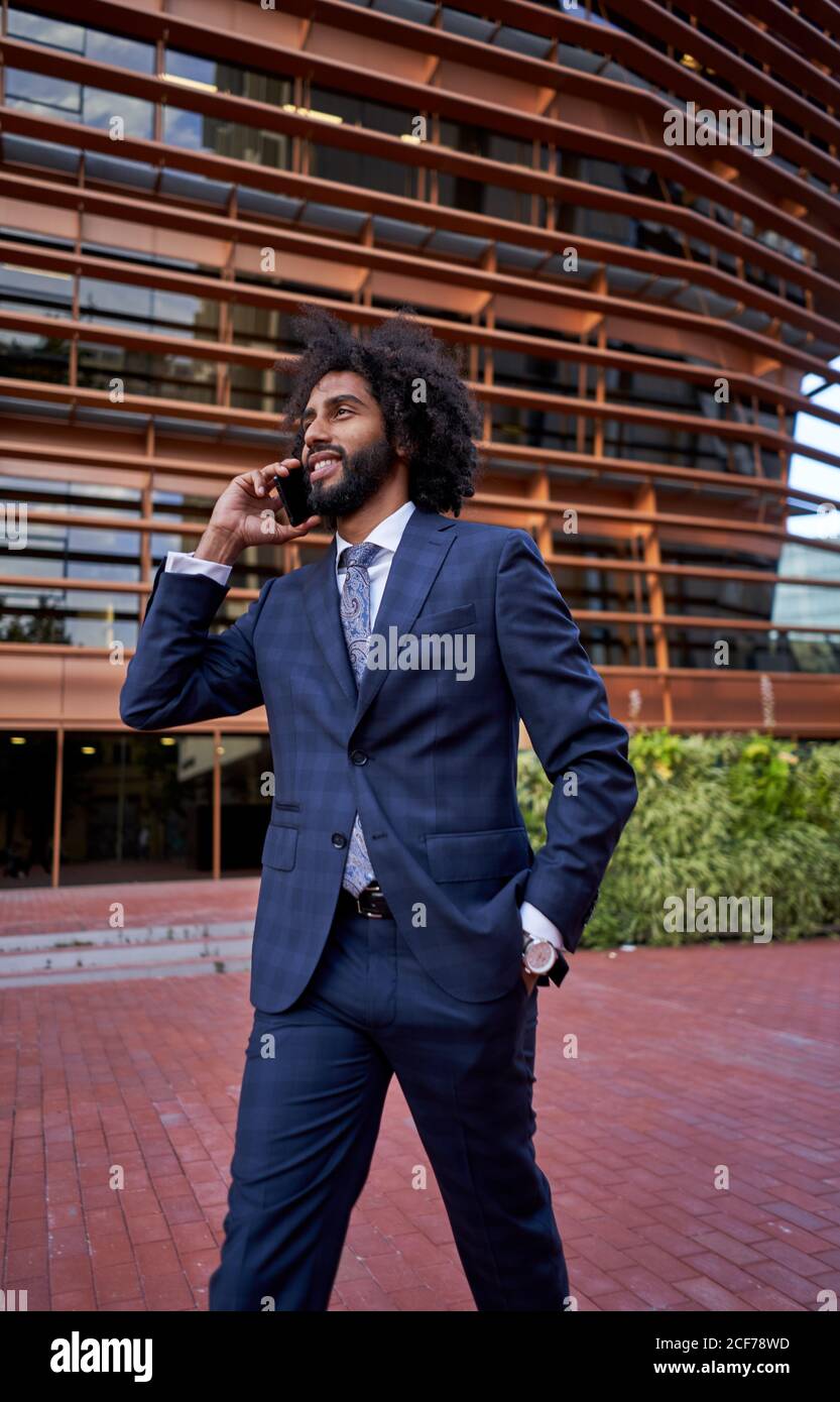 Ethnic smiling businessman talking on smartphone Stock Photo