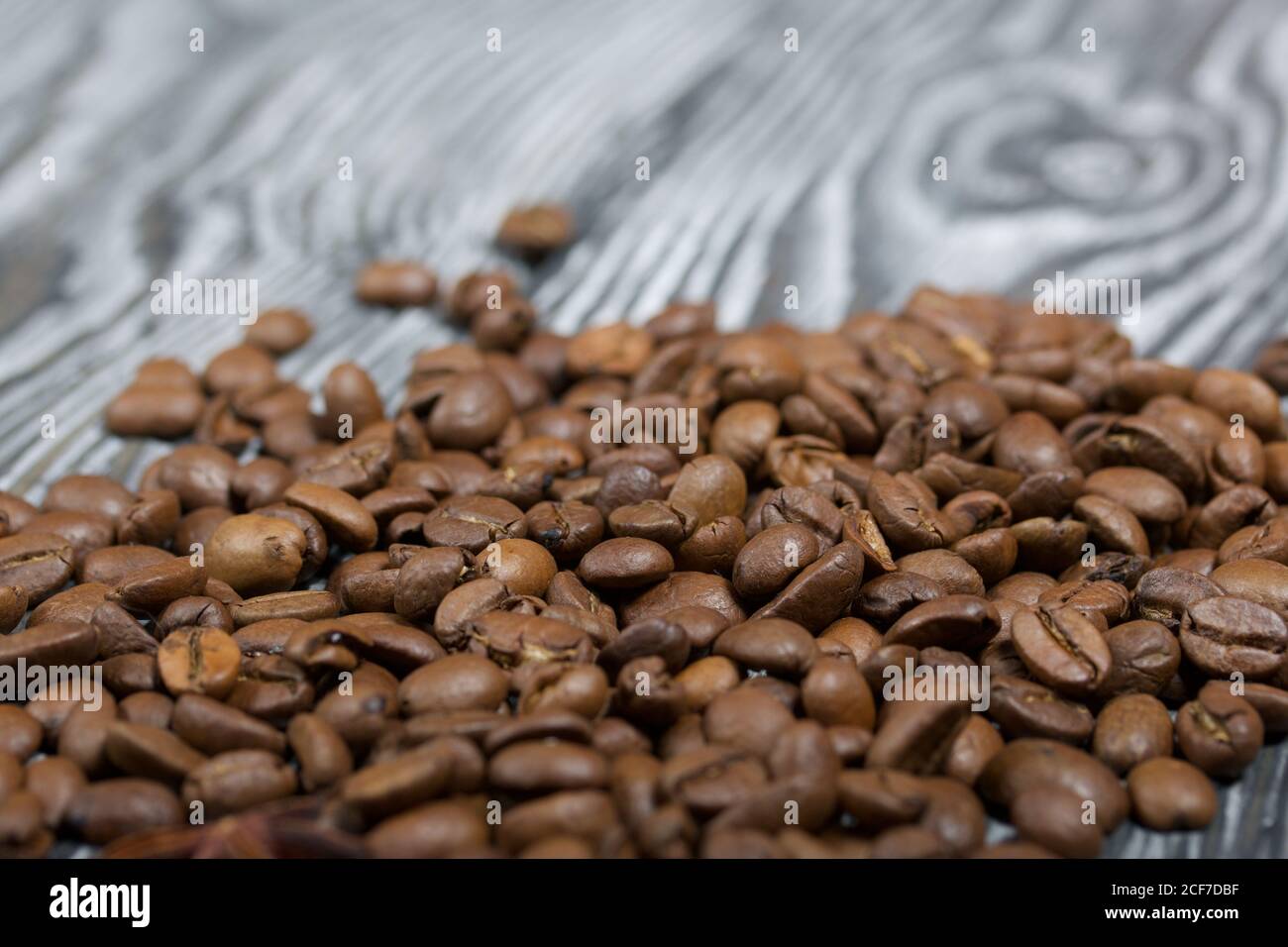 Coffee beans on a black-and-white brushed pine plank surface. Close-up shot. Stock Photo