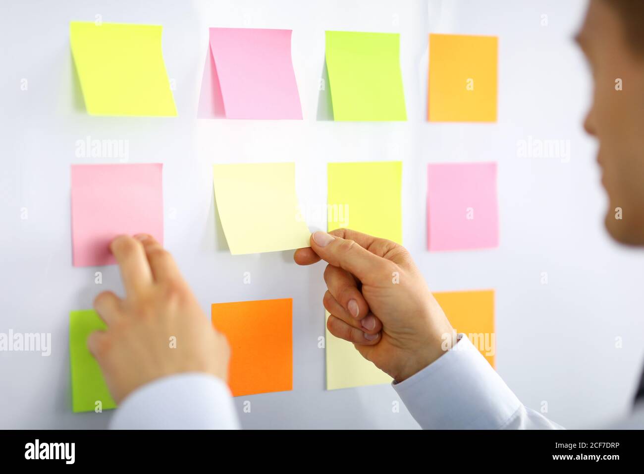 Male manager glues small notes on the wall Stock Photo