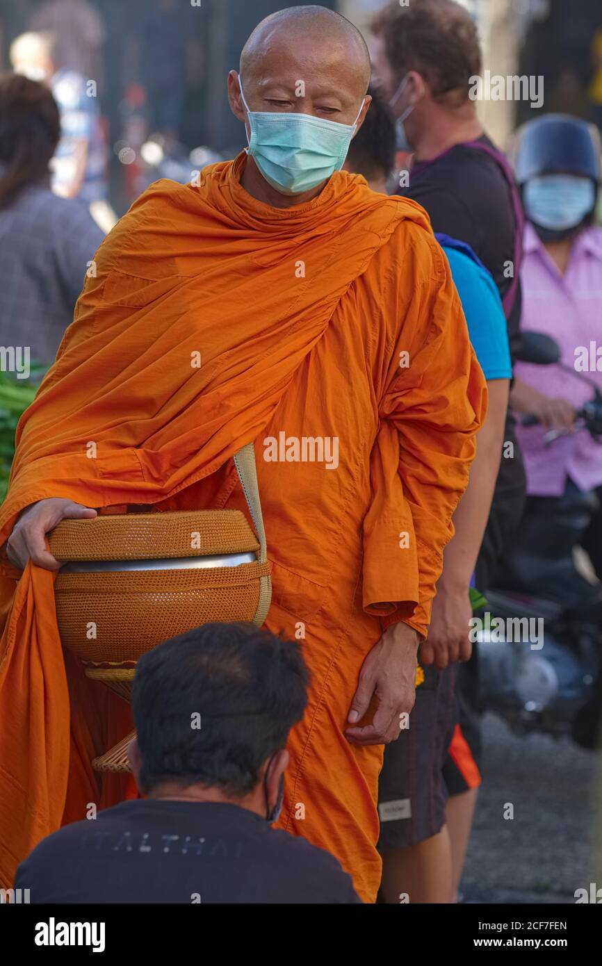 A devout Buddhist man kneels in front of a Buddhist monk on his traditional morning alms round (binta baat); Phuket Town, Thailand Stock Photo
