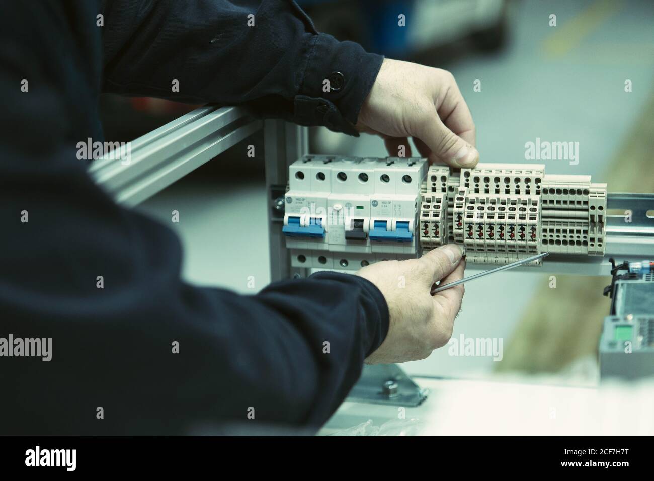 faceless male electrician in black shirt with multimeter probe in hand repairing electrical switchgear Stock Photo