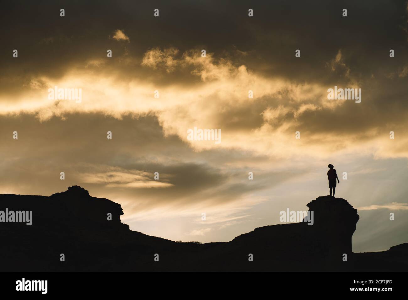 From below of male silhouette in motion on mountain with beautiful cloudy sky on background Stock Photo