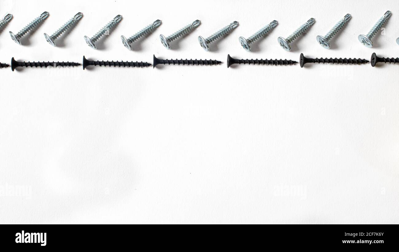 Self-cutters on a white background banner with space for text. Construction tools, self-tapping screws for fastening. Black screw hardware. Stock Photo