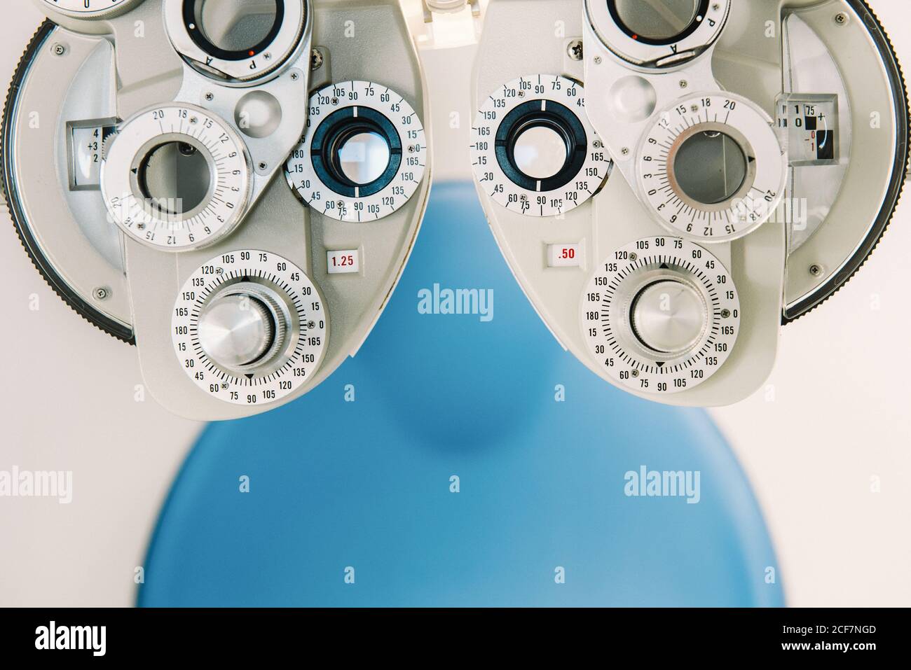 Modern vision test equipment and chair against white wall in optician