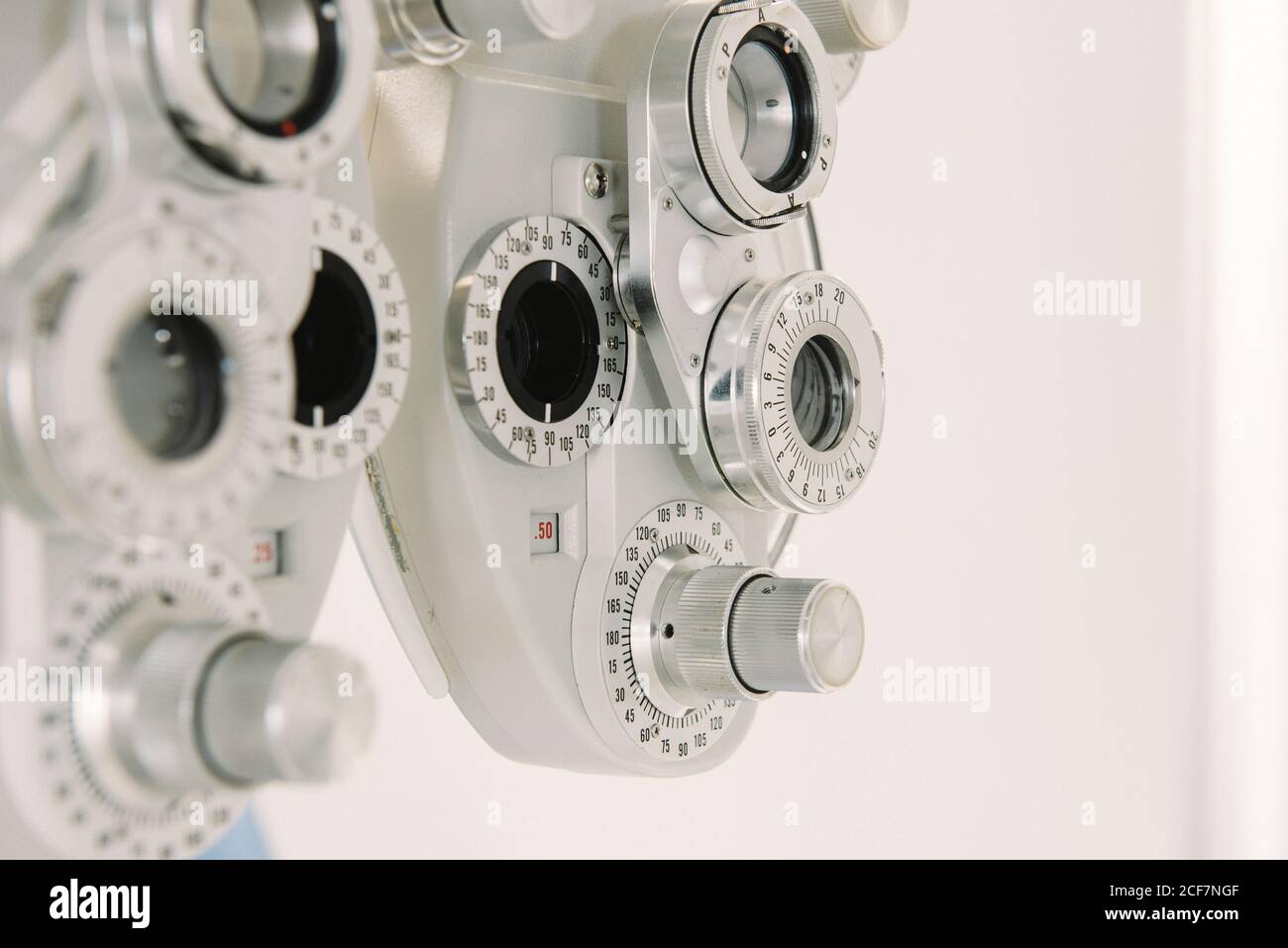 Modern vision test equipment and chair against white wall in optician