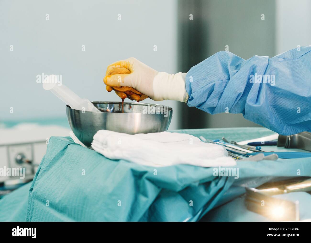 Crop hand of medic in blue gown and white glove squeezing tampon full of  iodine in bowl during surgery Stock Photo - Alamy